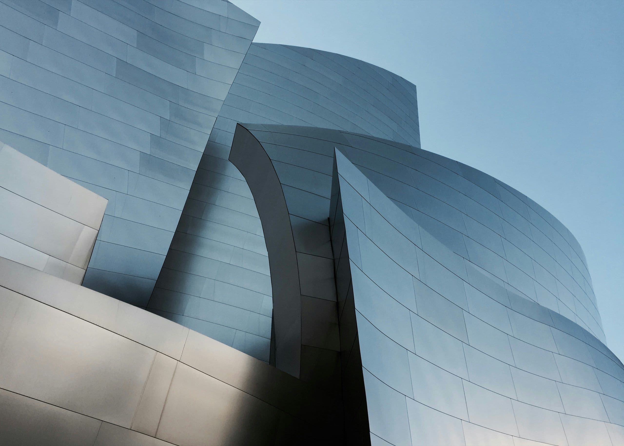 A curved metal-clad facade rising against an evening sky
